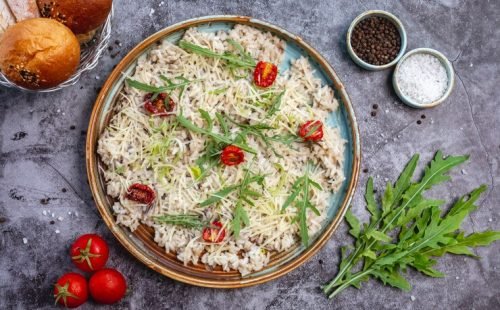 top-view-mushroom-risotto-garnished-with-shredded-cheese-dried-tomato-leaves_141793-2444